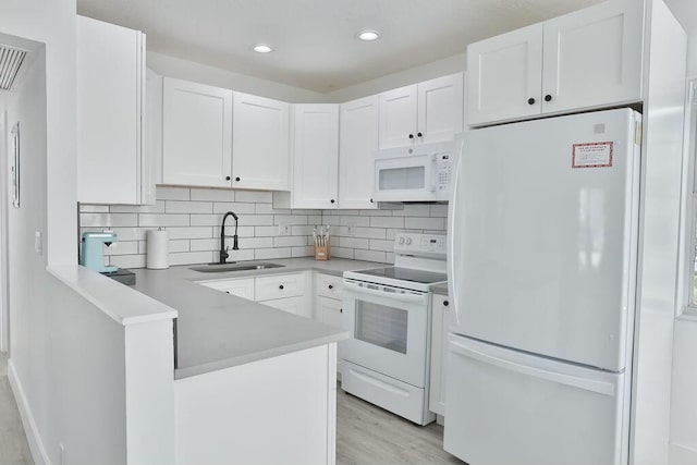 kitchen with white appliances, sink, light hardwood / wood-style flooring, tasteful backsplash, and white cabinetry