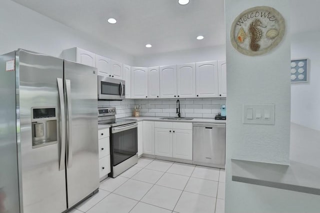 kitchen featuring decorative backsplash, appliances with stainless steel finishes, sink, white cabinetry, and light tile patterned flooring