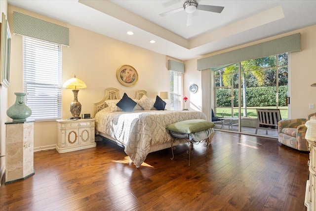 bedroom with access to exterior, dark hardwood / wood-style flooring, a raised ceiling, and ceiling fan