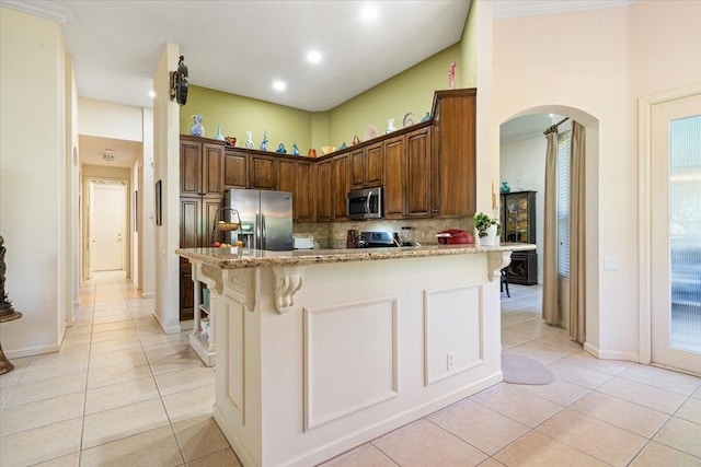 kitchen with stainless steel appliances, tasteful backsplash, light stone counters, a breakfast bar, and light tile patterned floors