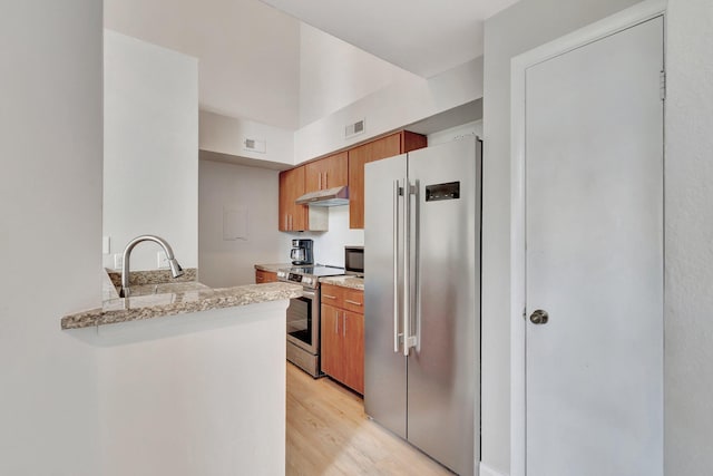 kitchen featuring sink, light stone counters, light hardwood / wood-style flooring, kitchen peninsula, and appliances with stainless steel finishes