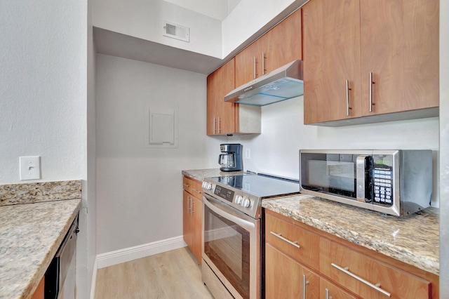 kitchen with light stone counters, light hardwood / wood-style flooring, and appliances with stainless steel finishes