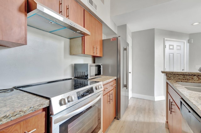 kitchen featuring light stone counters, sink, stainless steel appliances, and light hardwood / wood-style floors