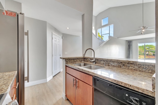 kitchen with light stone counters, dishwasher, lofted ceiling, and sink