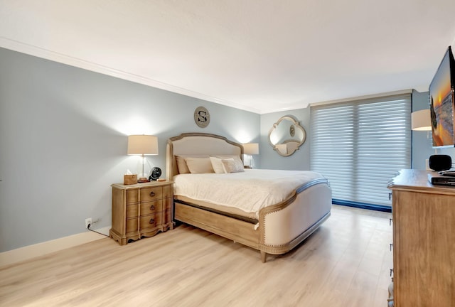 bedroom featuring crown molding and light hardwood / wood-style flooring