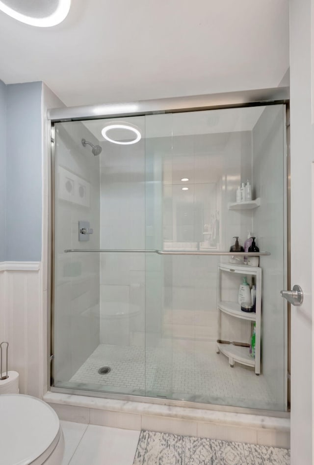 bathroom with an enclosed shower, toilet, and tile patterned floors