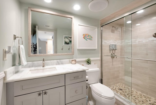 bathroom featuring vanity, a shower with shower door, and toilet