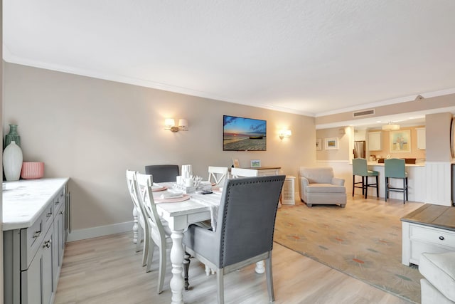 dining space with crown molding and light hardwood / wood-style flooring