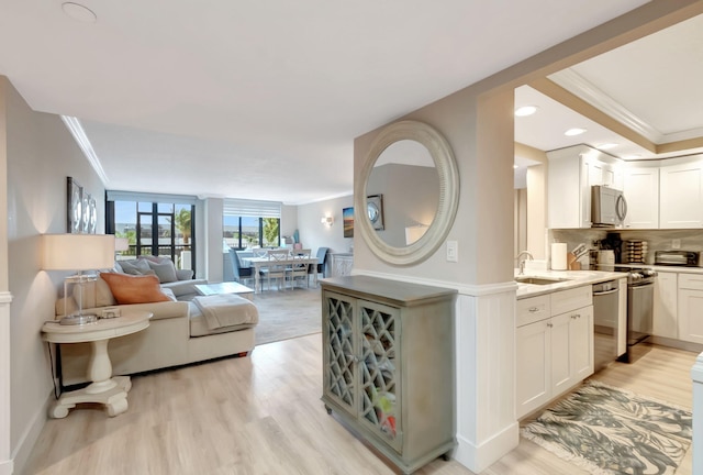 kitchen with white cabinetry, sink, backsplash, appliances with stainless steel finishes, and light wood-type flooring