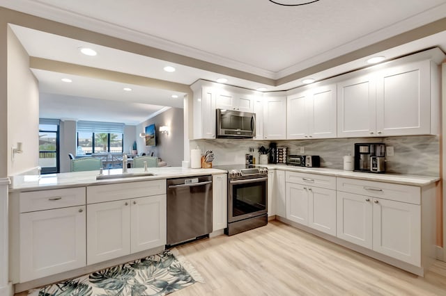 kitchen with sink, stainless steel appliances, light hardwood / wood-style flooring, white cabinets, and ornamental molding