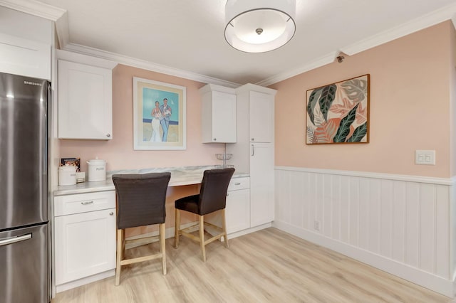 kitchen featuring light hardwood / wood-style floors, stainless steel fridge, white cabinetry, and crown molding