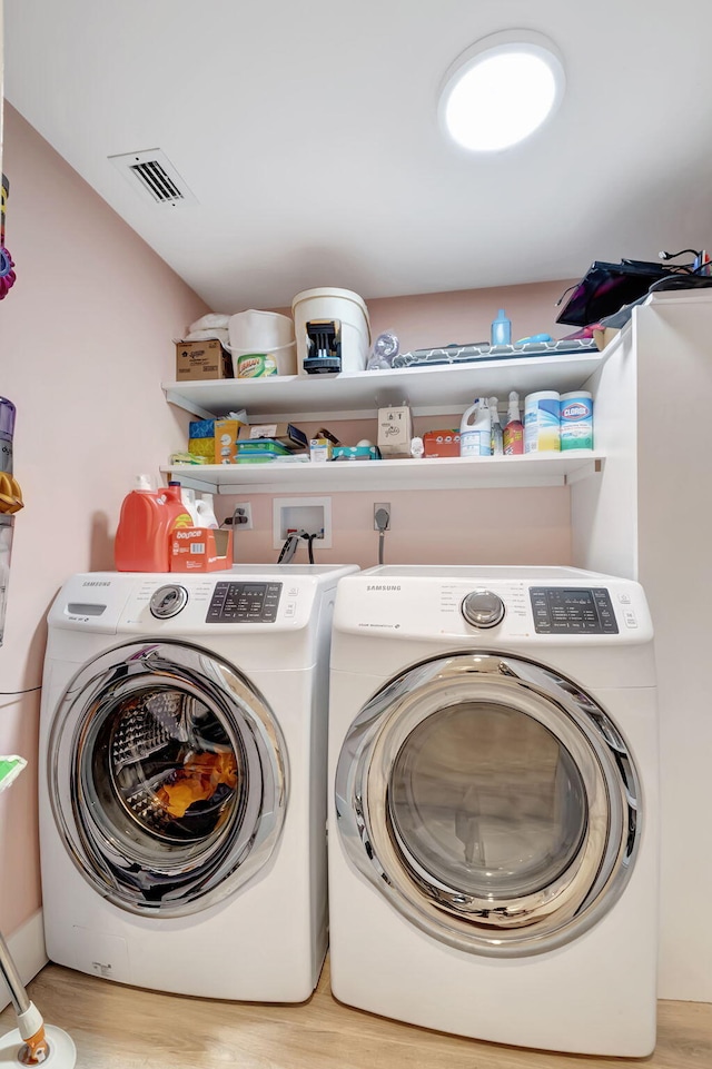 laundry area with light hardwood / wood-style floors and washing machine and dryer