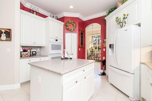 kitchen featuring white appliances, white cabinets, crown molding, light tile patterned floors, and a kitchen island