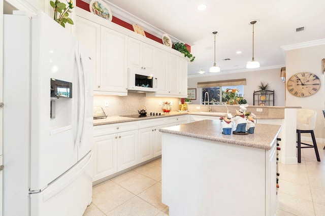 kitchen with white cabinetry, hanging light fixtures, a kitchen breakfast bar, white appliances, and a kitchen island