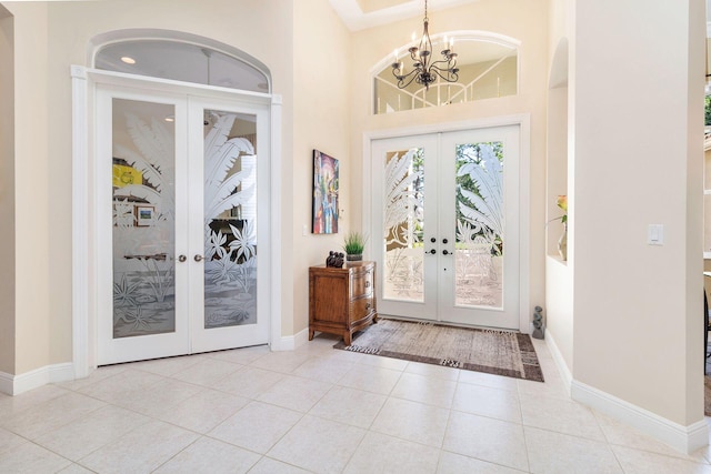 tiled foyer entrance with french doors, a high ceiling, and an inviting chandelier