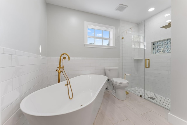 bathroom with tile patterned floors, toilet, tile walls, and independent shower and bath