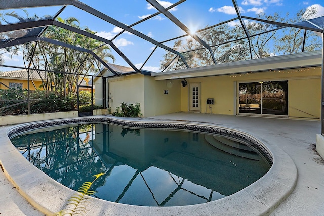 view of pool with glass enclosure and a patio