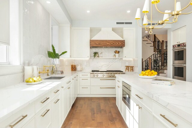 230 Argyle Rd, West Palm Beach, FL 33405 - kitchen with custom range hood, appliances with stainless steel finishes, open shelves, light stone countertops, and decorative backsplash