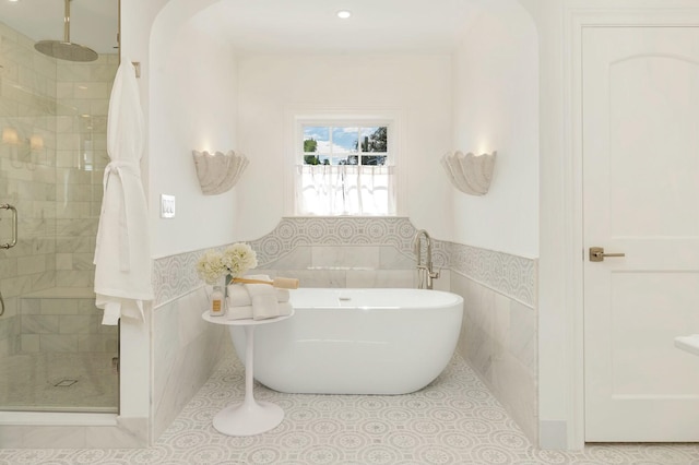 230 Argyle Rd, West Palm Beach, FL 33405 - full bathroom with tile walls, a stall shower, a soaking tub, a wainscoted wall, and tile patterned flooring