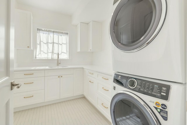 laundry room featuring cabinets, sink, and stacked washing maching and dryer