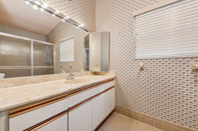 bathroom featuring tile patterned flooring, vanity, and vaulted ceiling