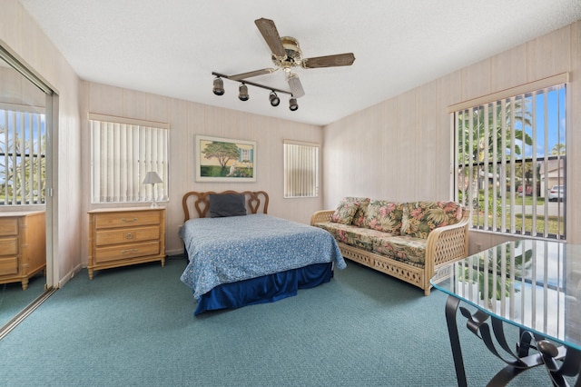 bedroom featuring a textured ceiling, ceiling fan, dark carpet, and track lighting