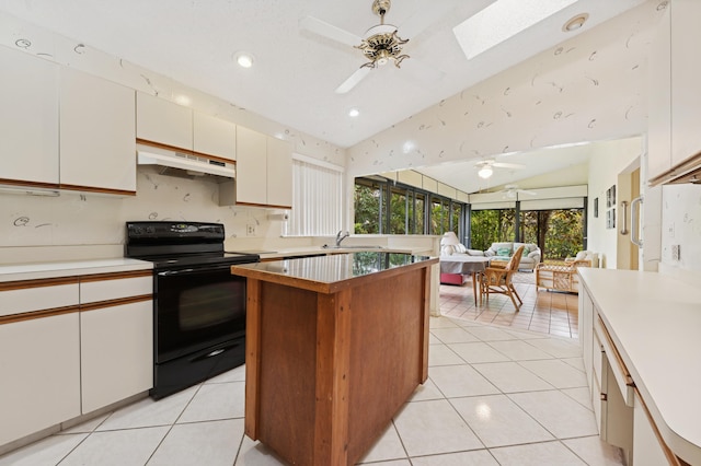 kitchen featuring lofted ceiling with skylight, black electric range, ceiling fan, and a kitchen island