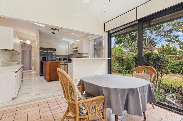 tiled dining area featuring ceiling fan and vaulted ceiling