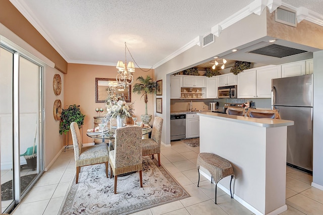 kitchen with white cabinets, ornamental molding, a textured ceiling, and appliances with stainless steel finishes