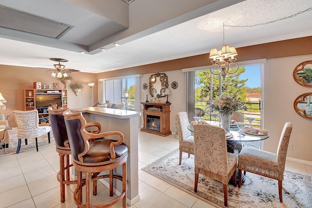 tiled dining room featuring ceiling fan with notable chandelier, a textured ceiling, and ornamental molding