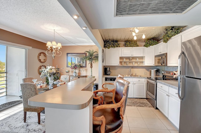 kitchen with an inviting chandelier, hanging light fixtures, light tile patterned floors, white cabinetry, and stainless steel appliances