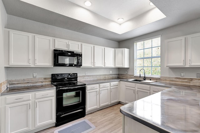 kitchen featuring white cabinets, light wood-type flooring, sink, and black appliances