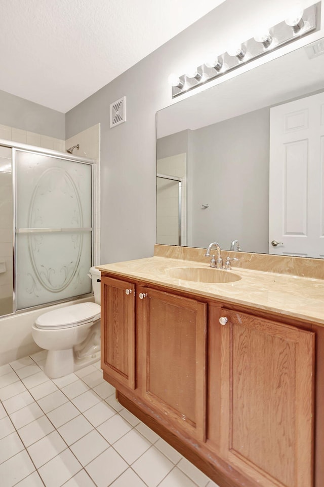 full bathroom featuring tile patterned flooring, bath / shower combo with glass door, a textured ceiling, toilet, and vanity