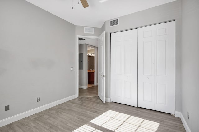 unfurnished bedroom with electric panel, ceiling fan, a closet, and light hardwood / wood-style flooring