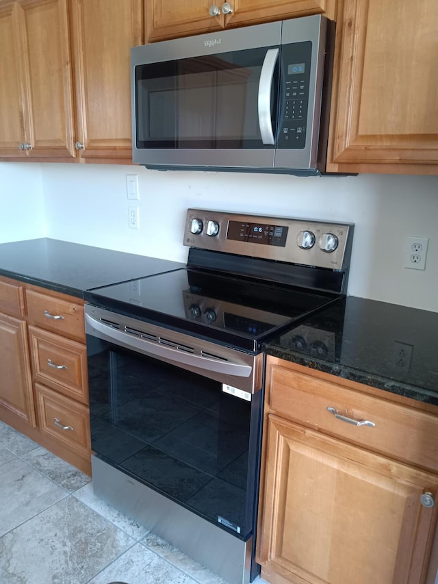 kitchen featuring appliances with stainless steel finishes and dark stone counters