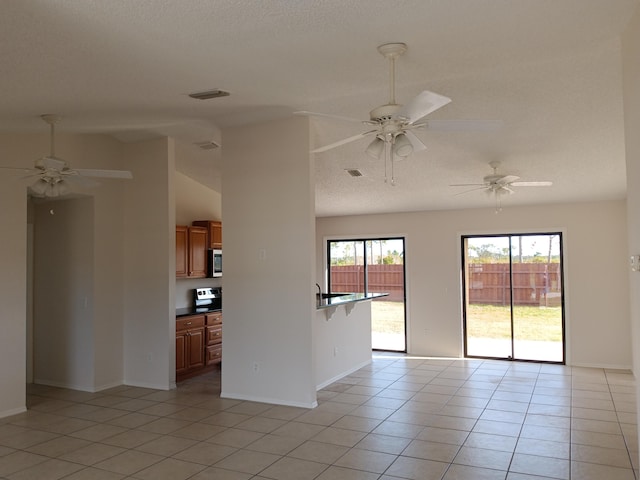 unfurnished room featuring light tile patterned floors, lofted ceiling, visible vents, a textured ceiling, and baseboards