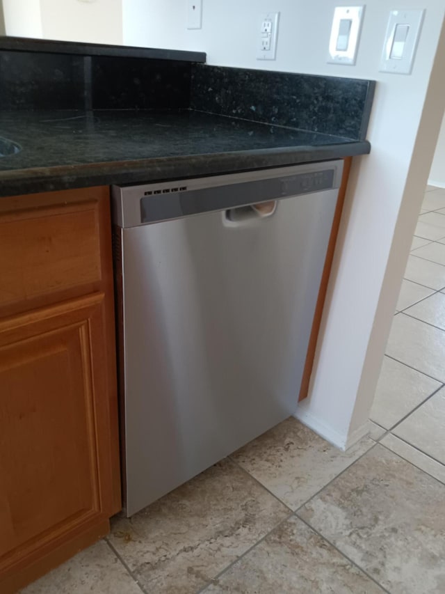 interior details with dark countertops, brown cabinets, and dishwasher