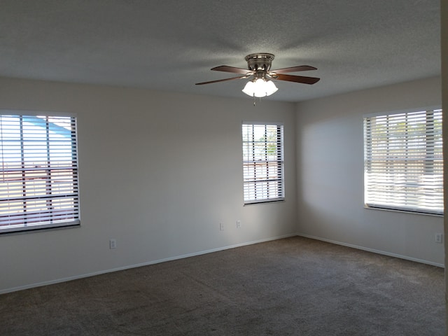 empty room with a textured ceiling, carpet, a ceiling fan, and baseboards