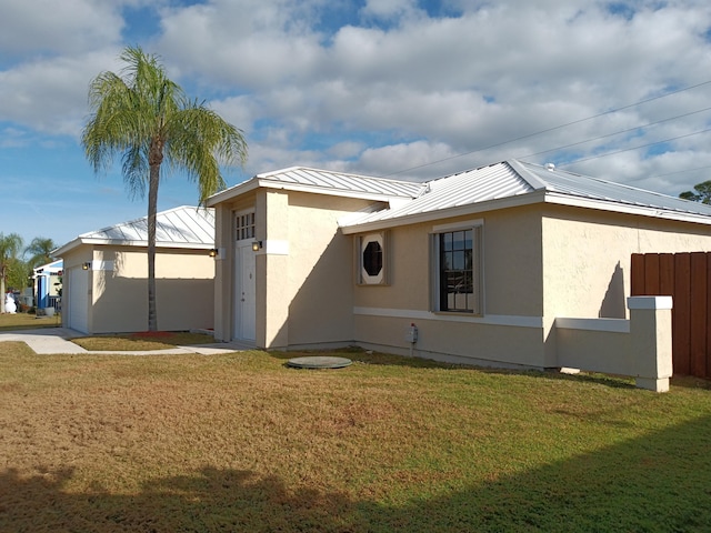 exterior space featuring metal roof, a lawn, fence, and stucco siding