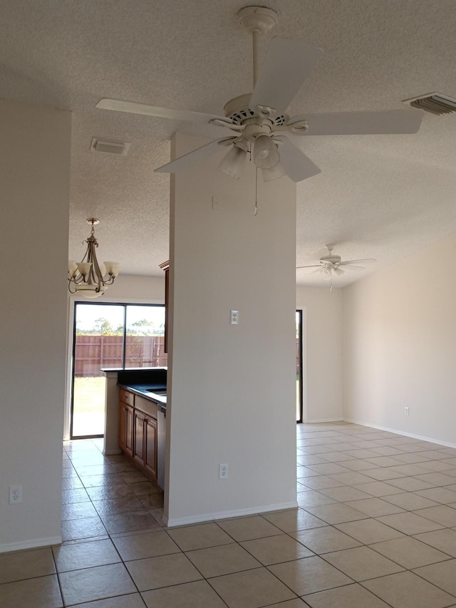 spare room with light tile patterned floors, visible vents, a textured ceiling, and ceiling fan with notable chandelier