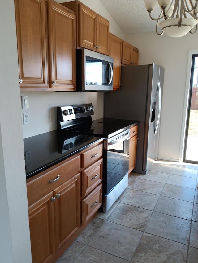 kitchen featuring a textured ceiling, appliances with stainless steel finishes, vaulted ceiling, and dark countertops