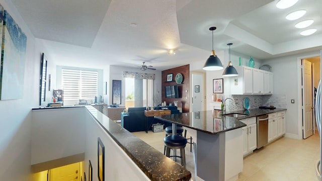 kitchen featuring a peninsula, white cabinetry, decorative backsplash, and a sink