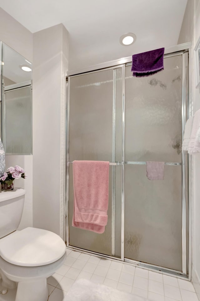 bathroom with tile patterned flooring, a shower with shower door, and toilet