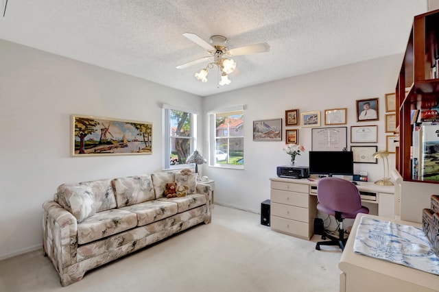 office space featuring ceiling fan, light colored carpet, and a textured ceiling