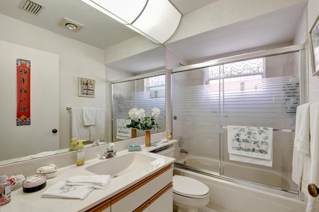 full bathroom with vanity, enclosed tub / shower combo, and toilet