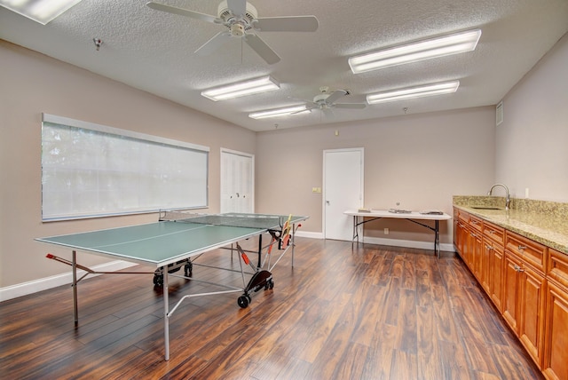 rec room with ceiling fan, dark hardwood / wood-style flooring, and a textured ceiling