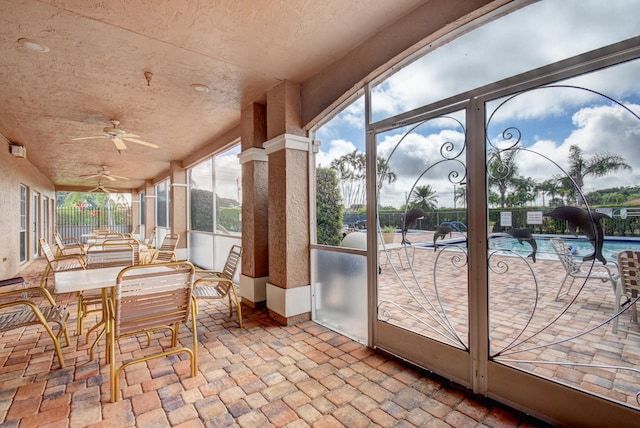 unfurnished sunroom with ceiling fan, a swimming pool, and vaulted ceiling