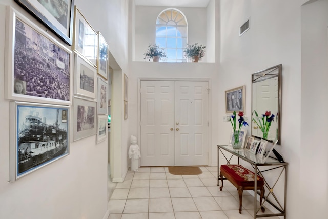 foyer entrance with light tile patterned floors and a towering ceiling