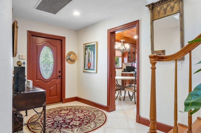 tiled entrance foyer with a chandelier