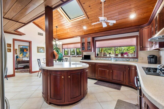 kitchen featuring pendant lighting, lofted ceiling with skylight, an island with sink, appliances with stainless steel finishes, and wood ceiling